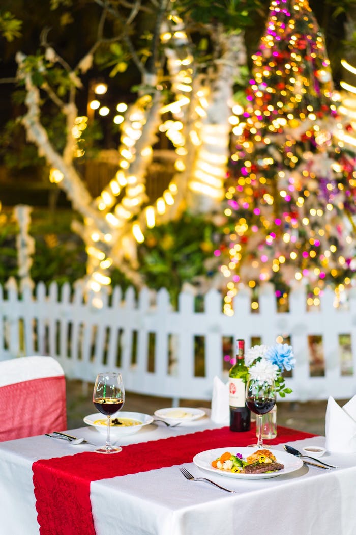 Intimate dining table set outdoors with wine and festive holiday decorations.
